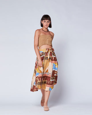 a women wearing an aztec printed circle skirt against a light grey background and a tan top. 