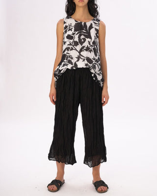 A model wearing a flowy floral pant with an elastic waist and a sleeveless floral top, standing against a white background.