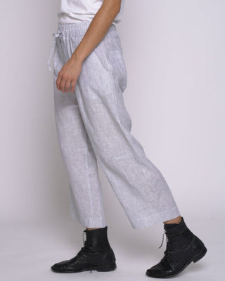 Woman wearing a white t-shirt and light gray pants against a white background