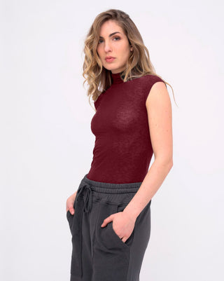 Woman wearing a red sleeveless top and gray pants on a white background